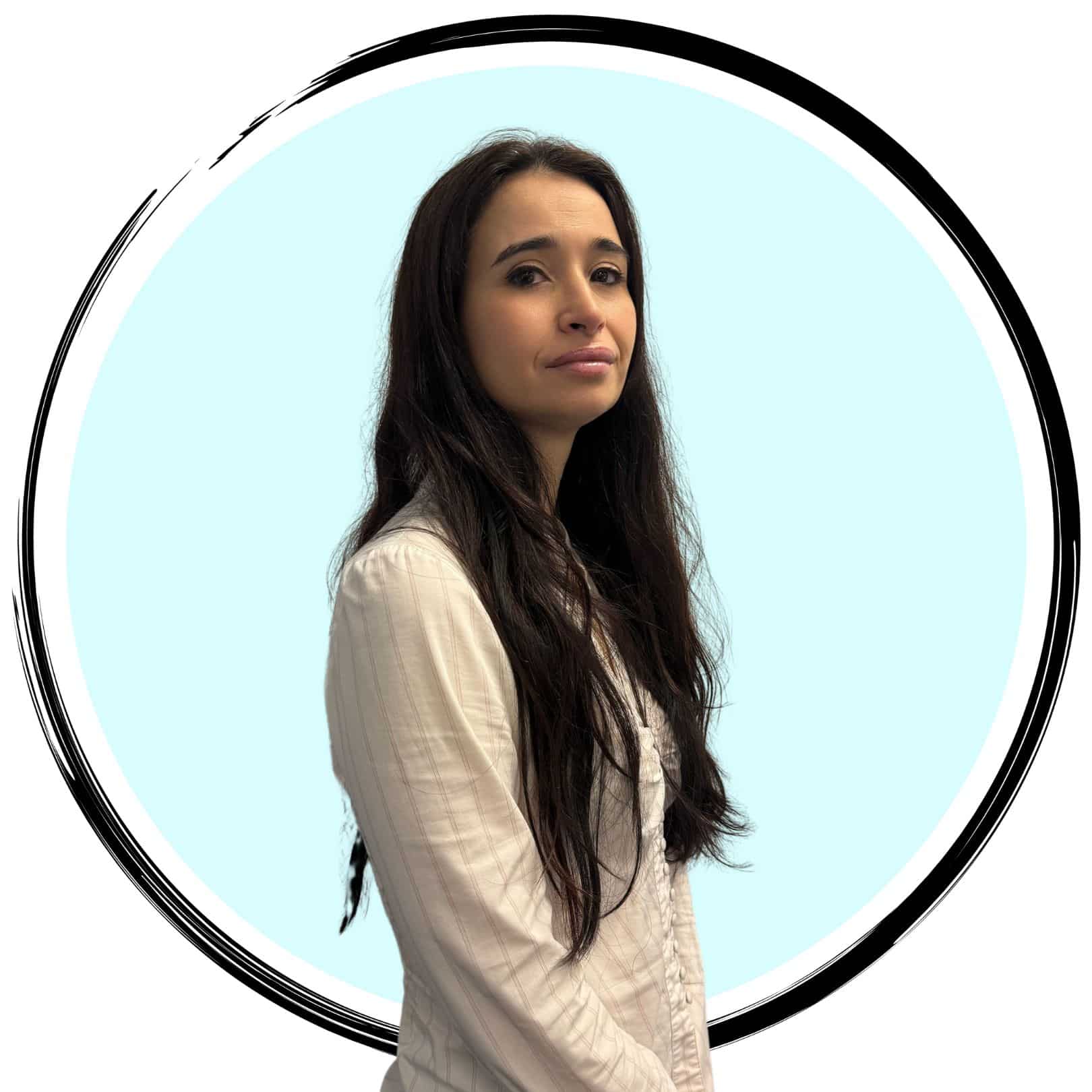 A woman with long, dark hair wearing a light-colored blouse stands against a round, light blue background with a black circular border. She is looking slightly to the left.